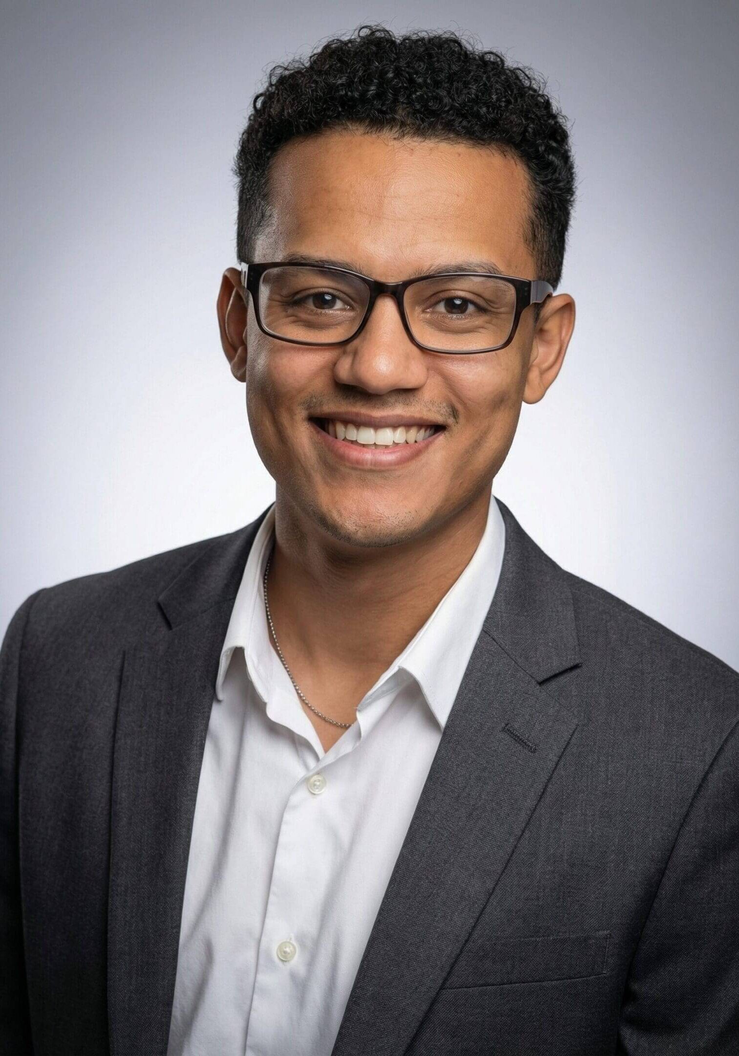 Smiling man in glasses and suit jacket.